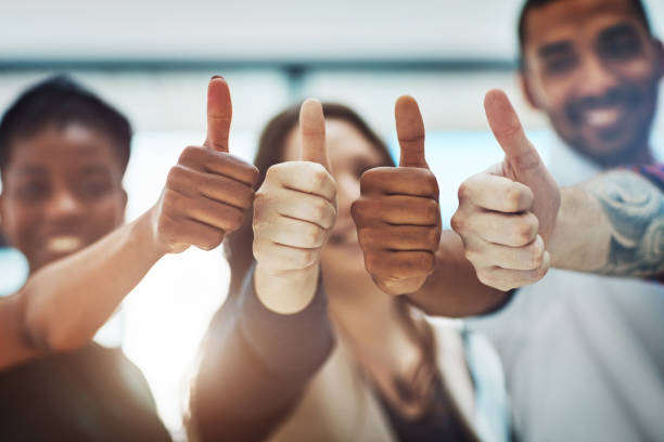 Go get that success! Cropped shot of a team of colleagues showing thumbs up at work congratulating stock pictures, royalty-free photos & images