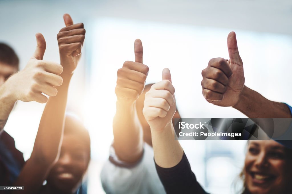 Bravo on your business accomplishment! Cropped shot of a team of colleagues showing thumbs up at work Achievement Stock Photo