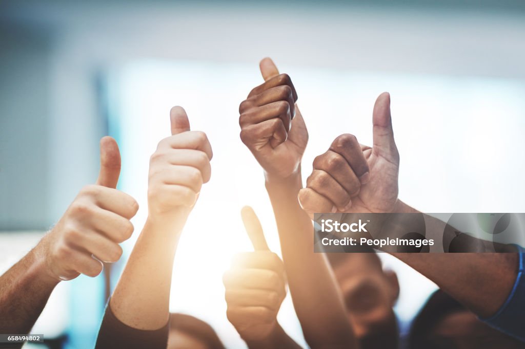 Keep up the amazing work! Cropped shot of a team of colleagues showing thumbs up at work Congratulating Stock Photo