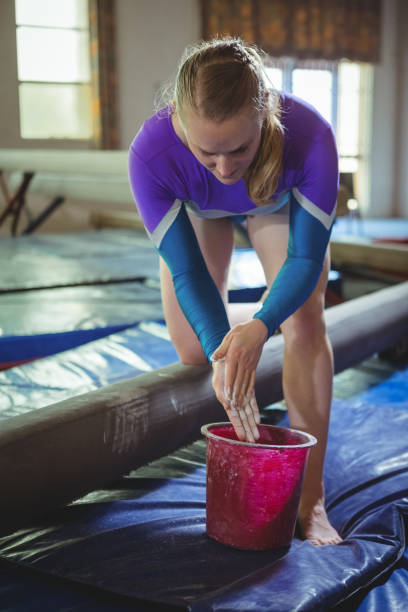 istock Female gymnast applying chalk powder on her hands before practicing 658494994