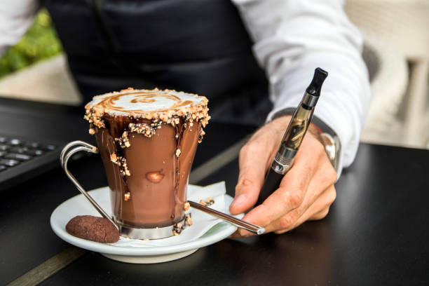 istock man with laptop sitting in cafe and smoking electronic cigarette. 658496232