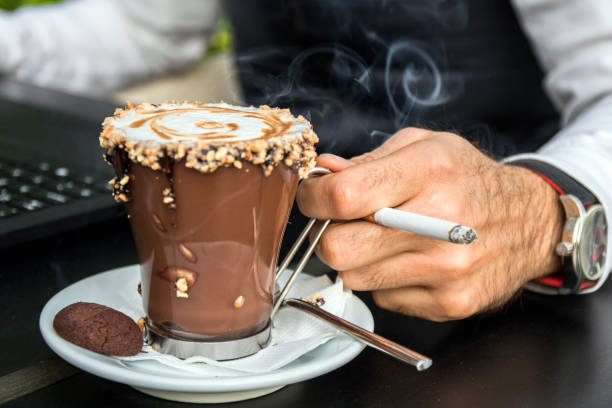 istock Hand holding a cigarette and a cup of coffee background. 658500998