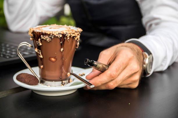 istock man holding vape or electronic cigarette and drinking coffee. 658503038