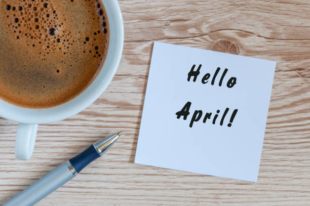 istock Hello April - notice on wooden table with morning coffee mug. Spring time concept 658506908
