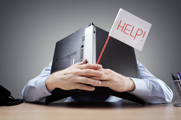 Businessman burying his head uner a laptop asking for help Frustrated and overworked businessman burying his head uner a laptop computer asking for help defeat stock pictures, royalty-free photos & images