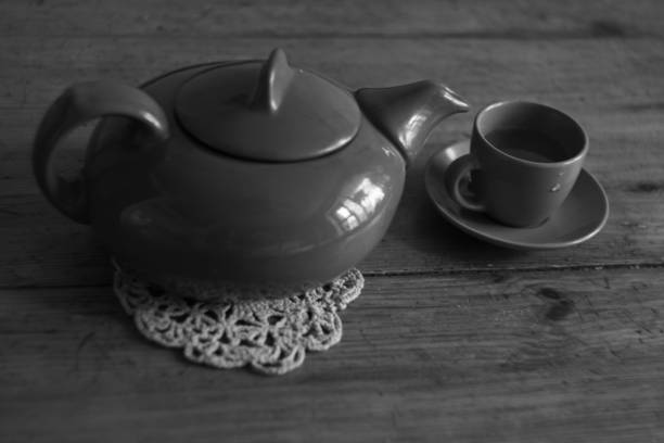 istock Breakfast time, tea pot and clay cup on wooden black and white background 658521332