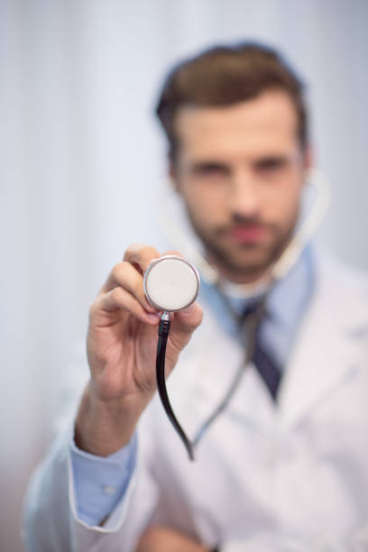 Close-up view of young male doctor holding stethoscope in hand