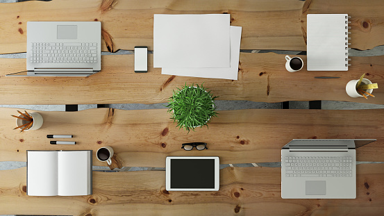 Business group scene showing hipster overhead office  desk close up, corporate teamwork template. laptop, tablet, PC monitor keyboard, notepad, paper. plant, mock up, no people
