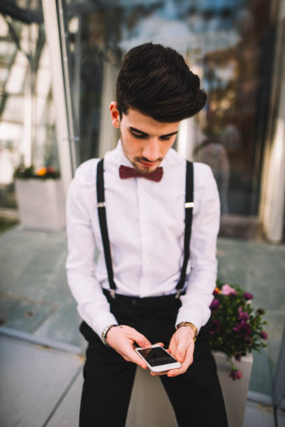 Young man using a smartphone A young man wearing a suit using an smartphone tecnología inalámbrica stock pictures, royalty-free photos & images