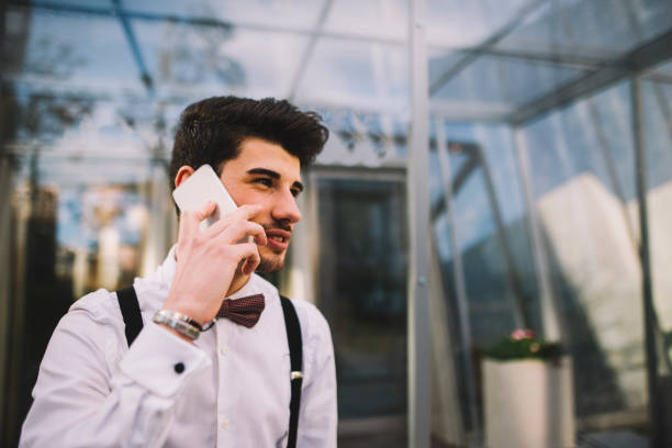 A young man wearing a suit and speaking on the phone