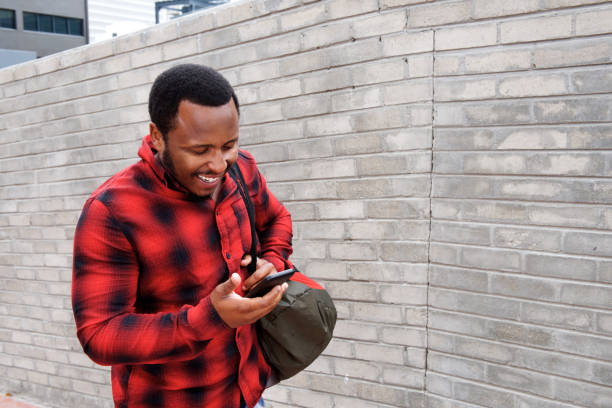 istock young black man walking with mobile phone and bag 658550956