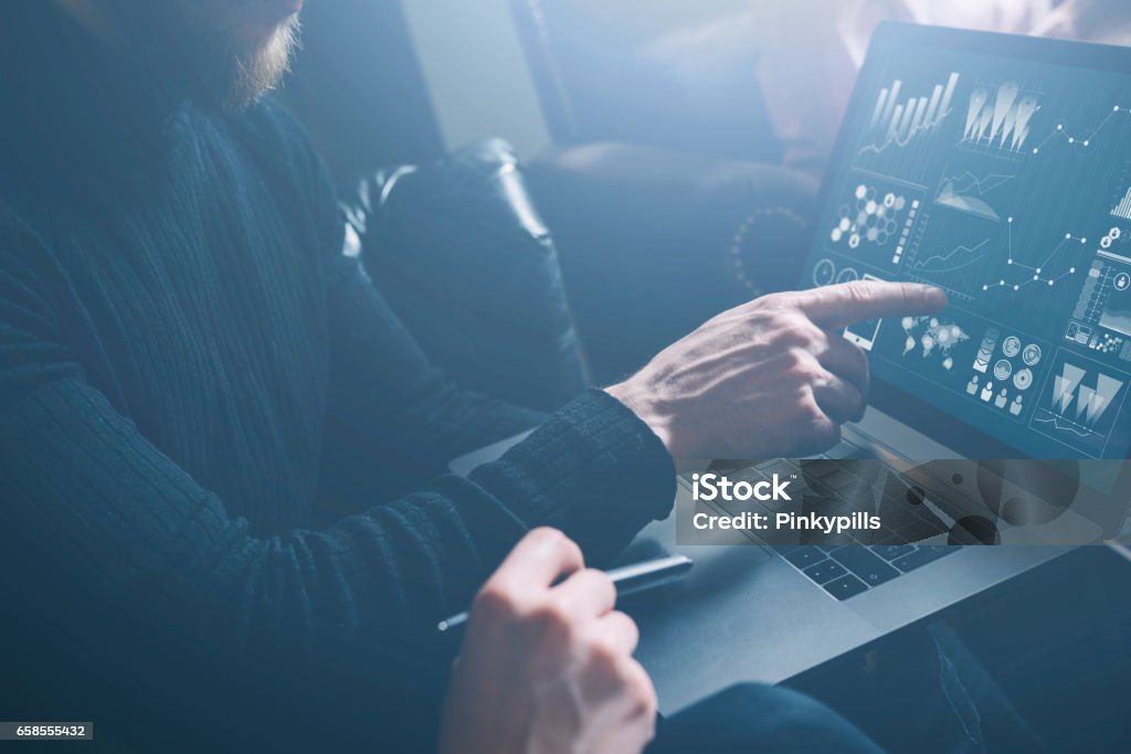 Young coworkers discussing business ideas at modern office.Bearded man poiting hand to laptop display.Woman sitting close him and holding pen on her hand. Horizontal, blurred, visual effect. Young coworkers discussing business ideas at modern office.Bearded man poiting hand to laptop display.Woman sitting close him and holding pen on her hand. Horizontal, blurred, visual effect Security Stock Photo