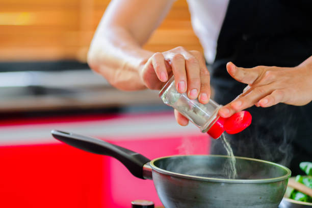 istock Private Thai chef cooking in a modern style home kitchen. Making Thai food, adding paper, face hidden. Close up hands 658556418