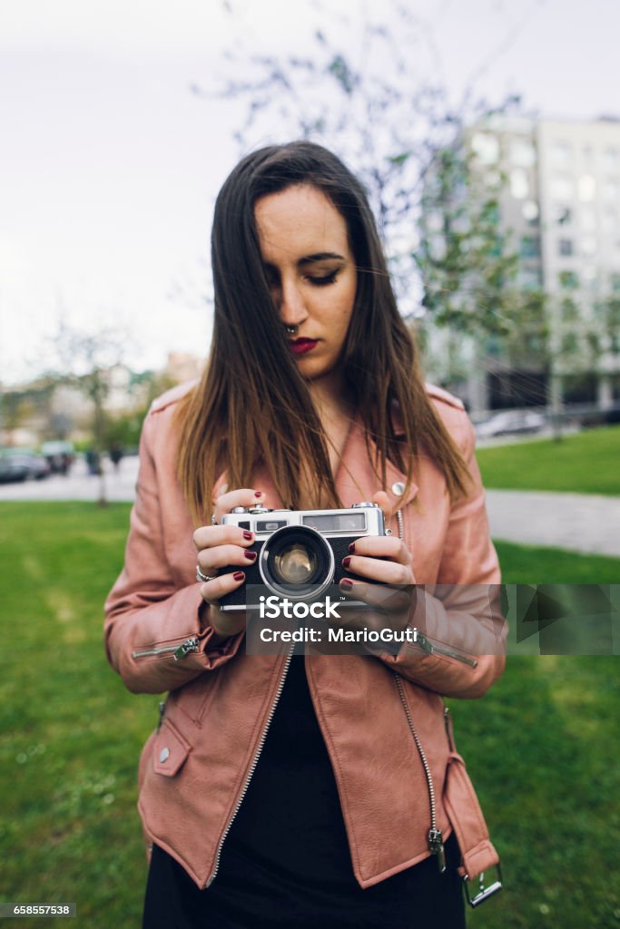 Young woman using a vintage camera A young woman using a vintage camera Adolescence Stock Photo