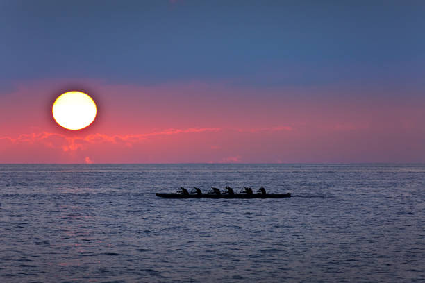 Outrigger Canoe at Sunset, Kailua-Kona, Hawaii The outrigger canoe, a local boat vessel in the Hawaiian culture. An outrigger rowing along the ocean at Kailua-Kona at sunset. outrigger stock pictures, royalty-free photos & images