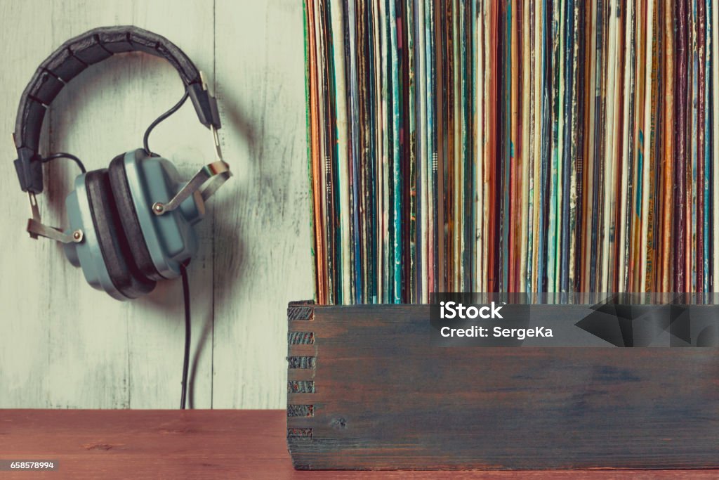 Old vinyl records and headphones Old vinyl records in a wooden box and headphones Record - Analog Audio Stock Photo