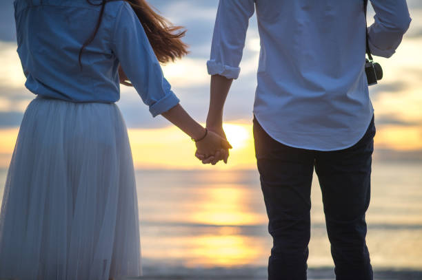 istock Couple holding hands beach scene 658580986