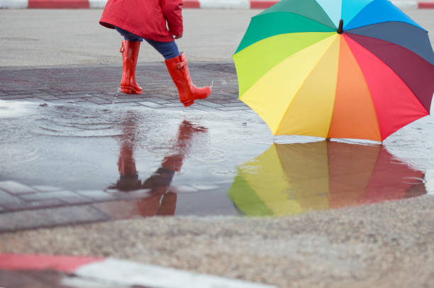 istock Jumping child with color umbrella in muddy puddle. 658587776