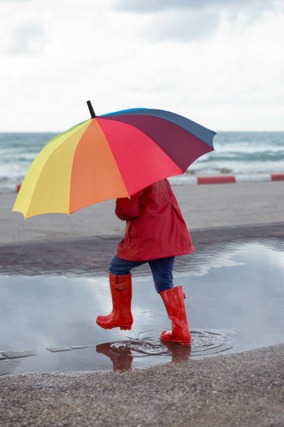 istock Kid with color umbrella stepping into a puddle. 658588814
