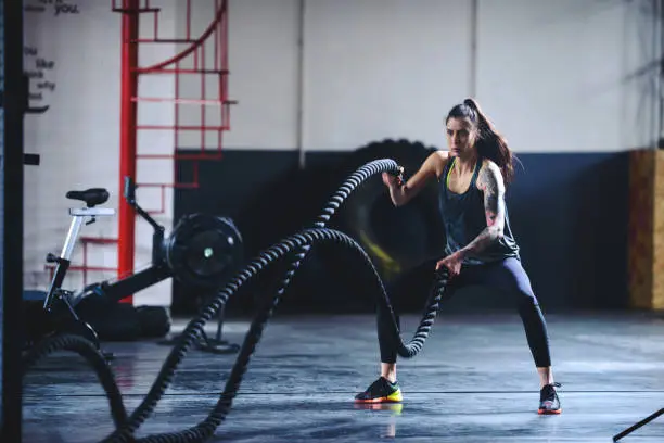 Woman working out with heavy ropes in the gym.