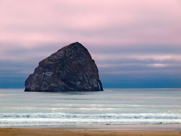 haystack rock góruje nad brzegiem w pobliżu przylądka kiwanda, oregon coast - cape kiwanda state park zdjęcia i obrazy z banku zdjęć