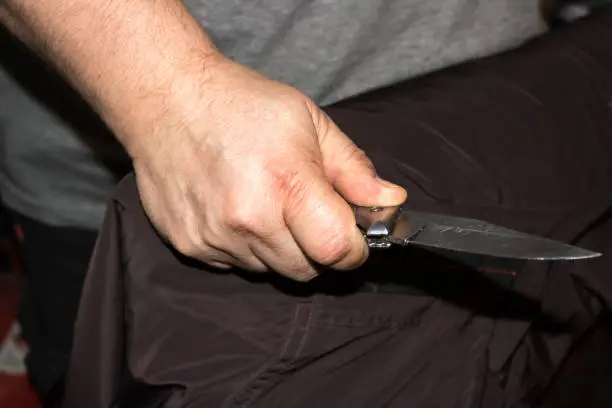 Closeup of a young man hand, holding a knife, about to attack,