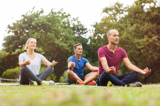 gruppe von menschen, die meditieren - yoga exercising outdoors group of people stock-fotos und bilder