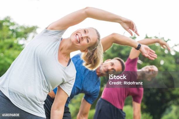 People Doing Stretching Exercise Stock Photo - Download Image Now - Exercising, Group Of People, Outdoors