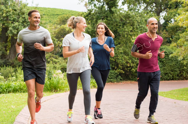 gruppo di persone mature che fanno jogging - exercising organized group sport outdoors foto e immagini stock