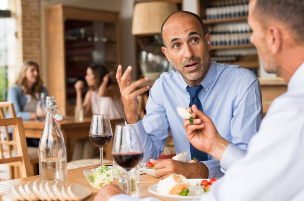Businessman having lunch Business people meeting at restaurant. Mature businessman in a conversation with partner in restaurant. Senior employee in talking abouth the new agreement with his colleague during lunch. business lunch stock pictures, royalty-free photos & images