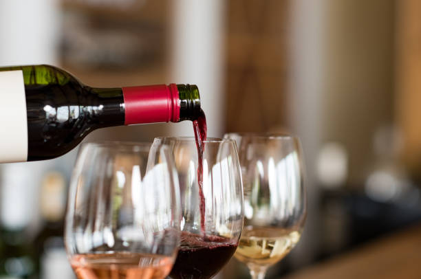 Pouring wine in glasses Pouring red wine from bottle into the wineglass on bar. Close up of red wine pouring from bottle to glass in a winery. Wine tasting in a winehouse. wine tasting stock pictures, royalty-free photos & images