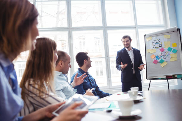 istock Coworkers looking at smiling businessman giving presentation 658616674