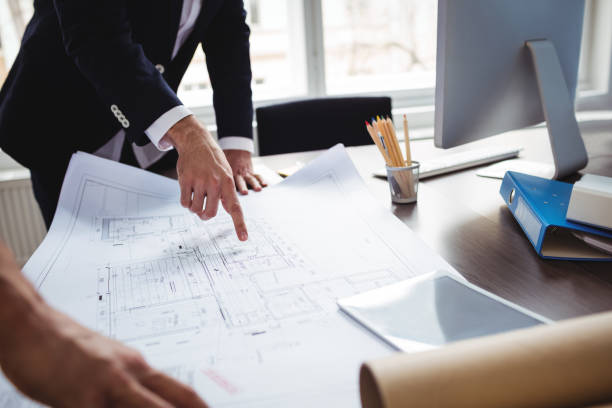 istock Manle interior designer discussing blueprint with coworker 658616778