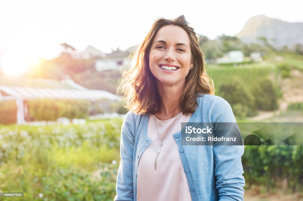 Laughing woman in park Cheerful mature woman enjoying in park during sunset. Happy hispanic woman in casual feeling relaxed outdoor. Smiling brunette woman looking at camera with carefree. Women Stock Photo