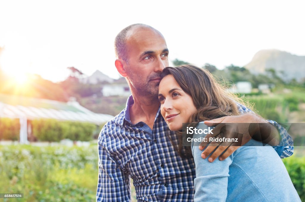 Mature couple in love Loving man and happy woman in a spring blooming park. Happy mature couple in love embracing outdoor. Hispanic boyfriend embracing her brunette girlfriend during sunset in a summer day. Couple - Relationship Stock Photo