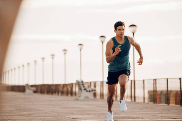 Male runner sprinting outdoors in morning Full length shot of healthy young man running on the promenade. Male runner sprinting outdoors. running stock pictures, royalty-free photos & images