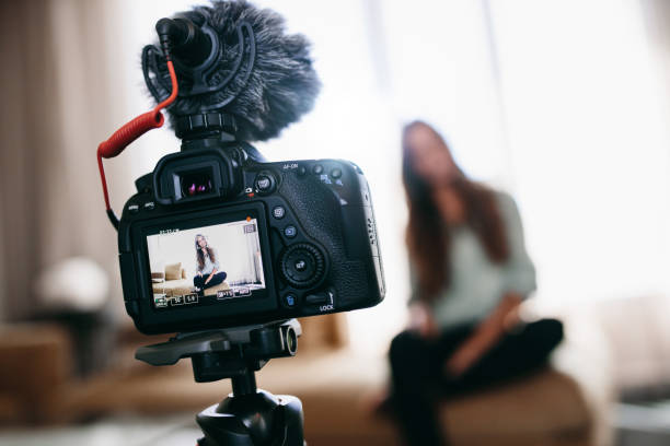 istock Young woman recording video for her vlog using camera with microphone mounted on tripod. 658621376