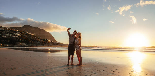 amante joven pareja tomando selfie en la playa - pareja joven fotos fotografías e imágenes de stock