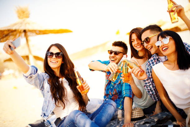 istock Happy young people having fun on the beach drinking beer and doing selfie 658628240