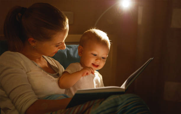 la madre lee a libro del bebé en la cama - baby mother sleeping child fotografías e imágenes de stock