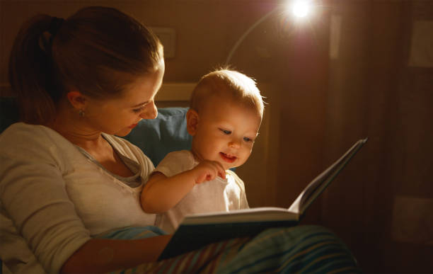 mère se lit à livre de bébé dans son lit - baby book toddler reading photos et images de collection