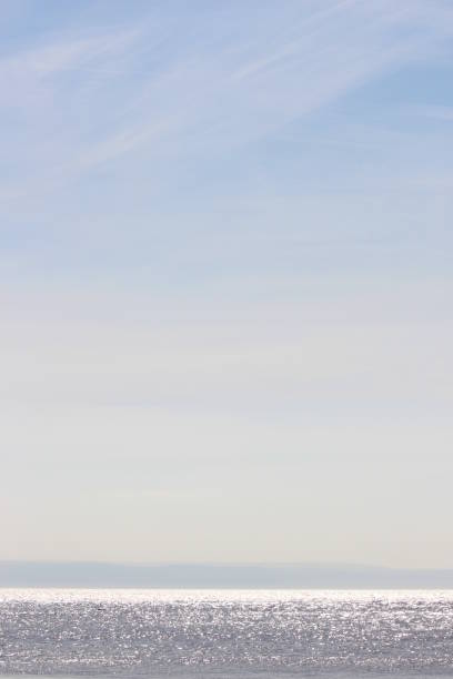 A photograph of a spring day at a British beach, sparkling ocean and white wispy clouds in the blue sky