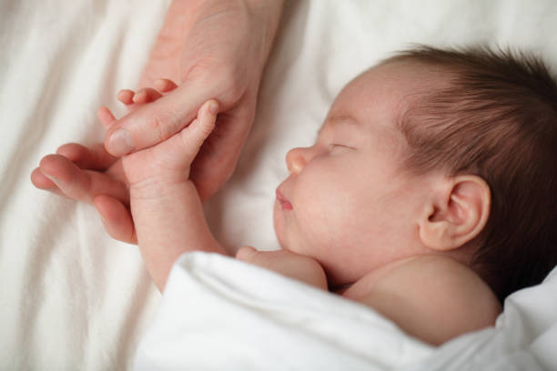 istock Happy newborn - baby sleeping and holding his father's hand 658631408