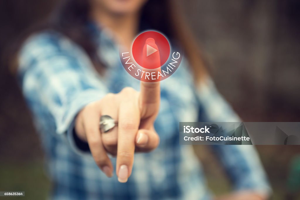 Live streaming. Woman pressing live streaming play button on digital display. Person tracking live event on the internet and touching livestream web button on touch screen. Live Streaming Stock Photo
