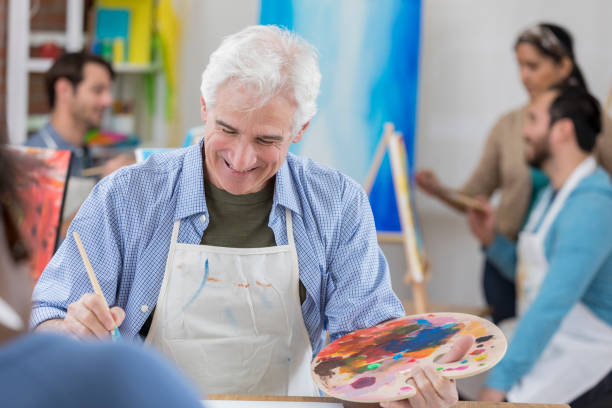istock Cheerful active senior man paints in art studio 658645966