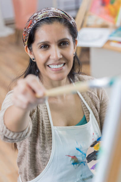 istock Woman concentrates while painting in art studio 658645970