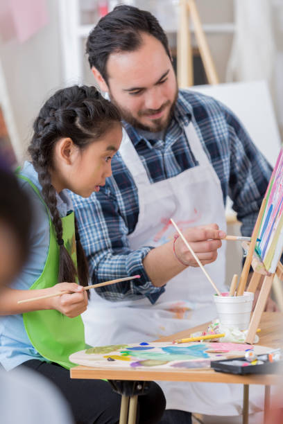 istock Hispanic art teacher works with young student 658647090