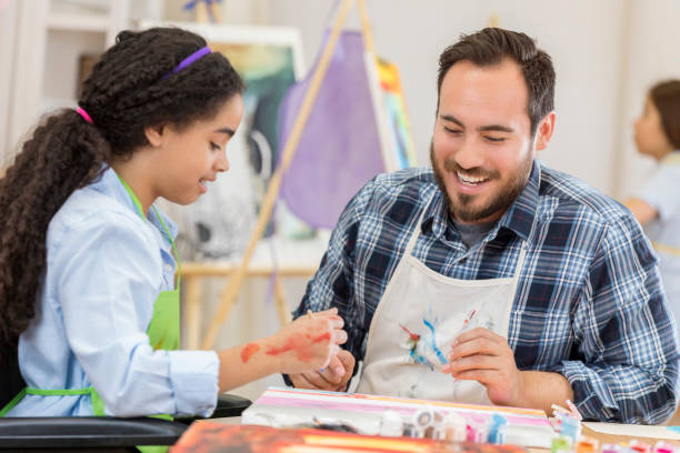 istock Cheerful art teacher helps young female student 658647116