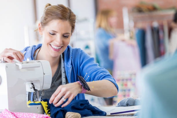 confident woman uses a sewing machine - manual worker sewing women tailor imagens e fotografias de stock