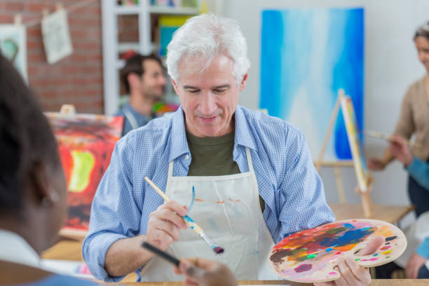 istock Senior man works on painting in art class 658649482